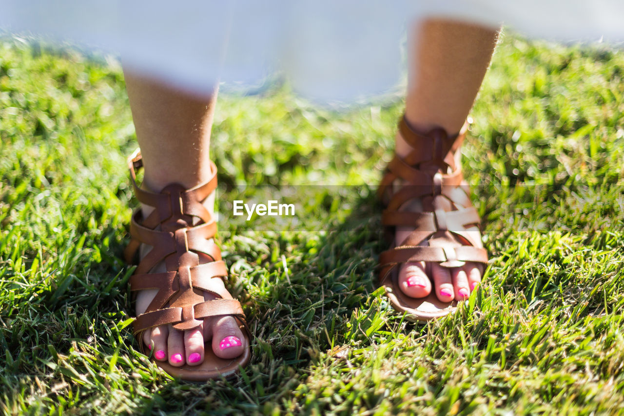 LOW SECTION OF WOMAN STANDING ON GRASSLAND