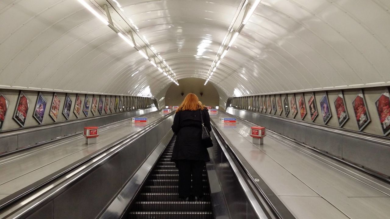 Rear view of woman on escalator at london underground