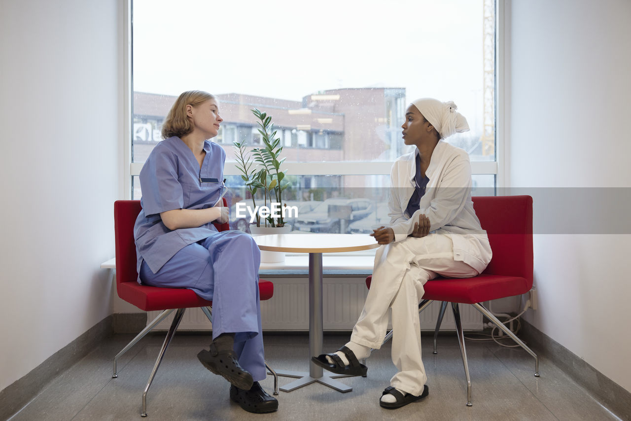 Female doctors sitting in hospital and talking to each other