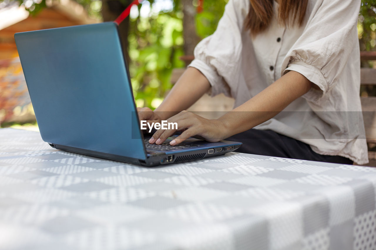 Hands of a woman pressing a notebook computer keyboard to do some work or search for information.