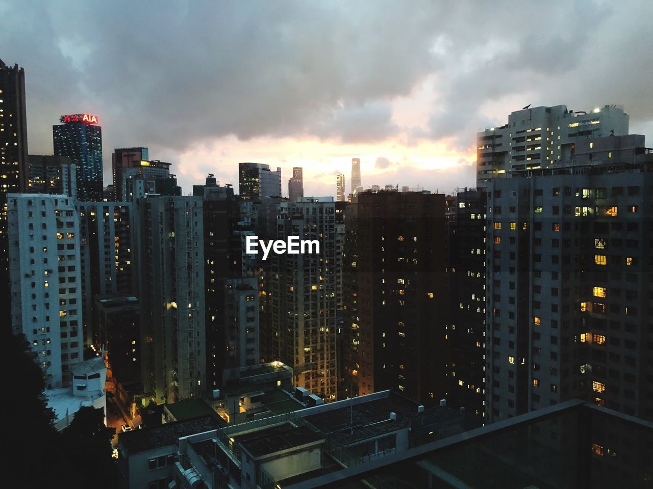 Illuminated buildings in city against sky at sunset