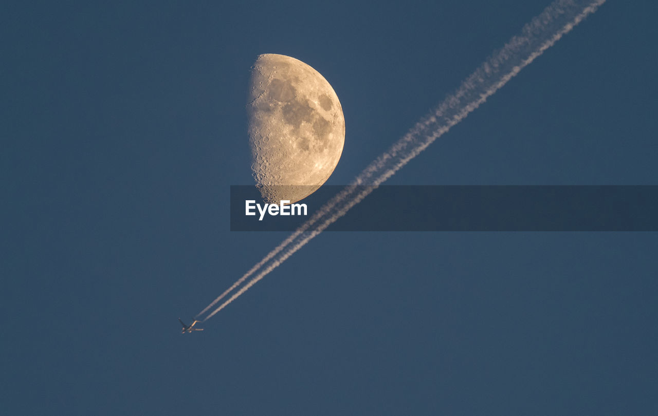 Low angle view of airplane against  moon and clear sky at night