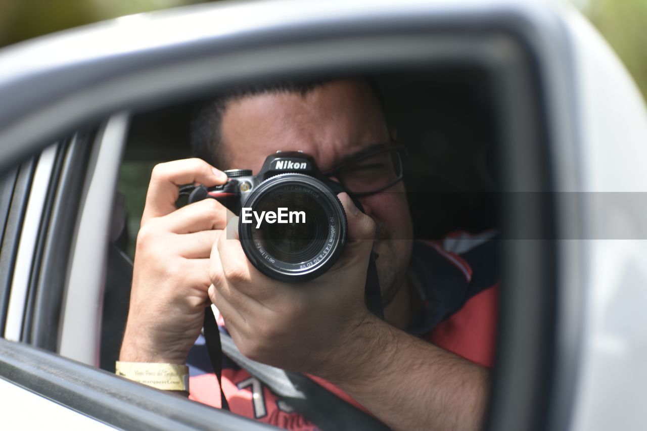 CLOSE-UP PORTRAIT OF MAN PHOTOGRAPHING CAMERA