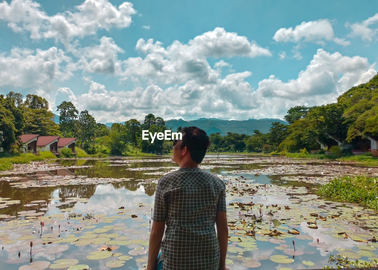 Rear view of man standing against pond