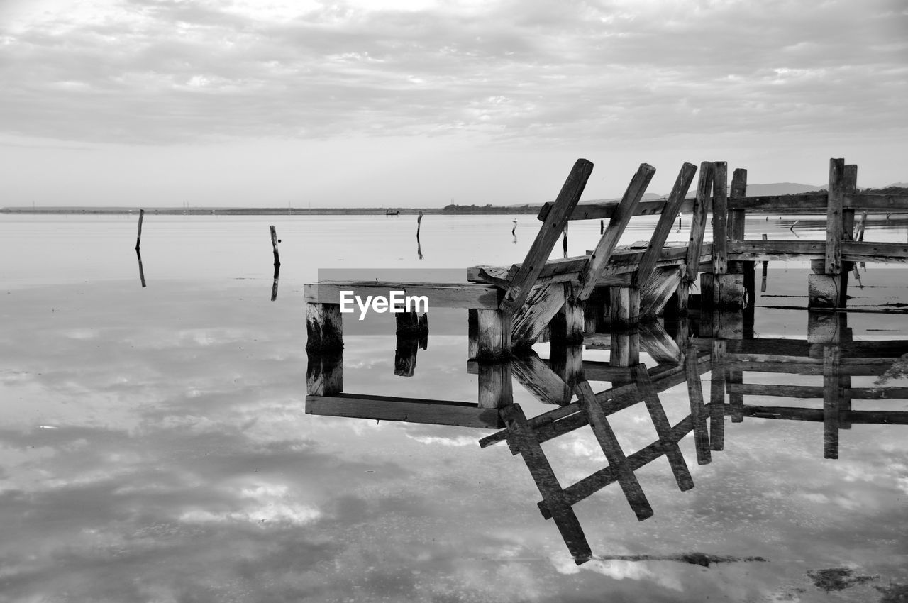 Wooden posts on sea against sky