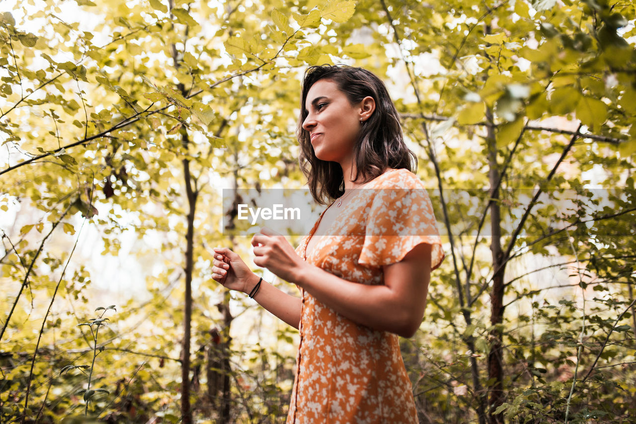 Smiling woman standing amidst trees in forest