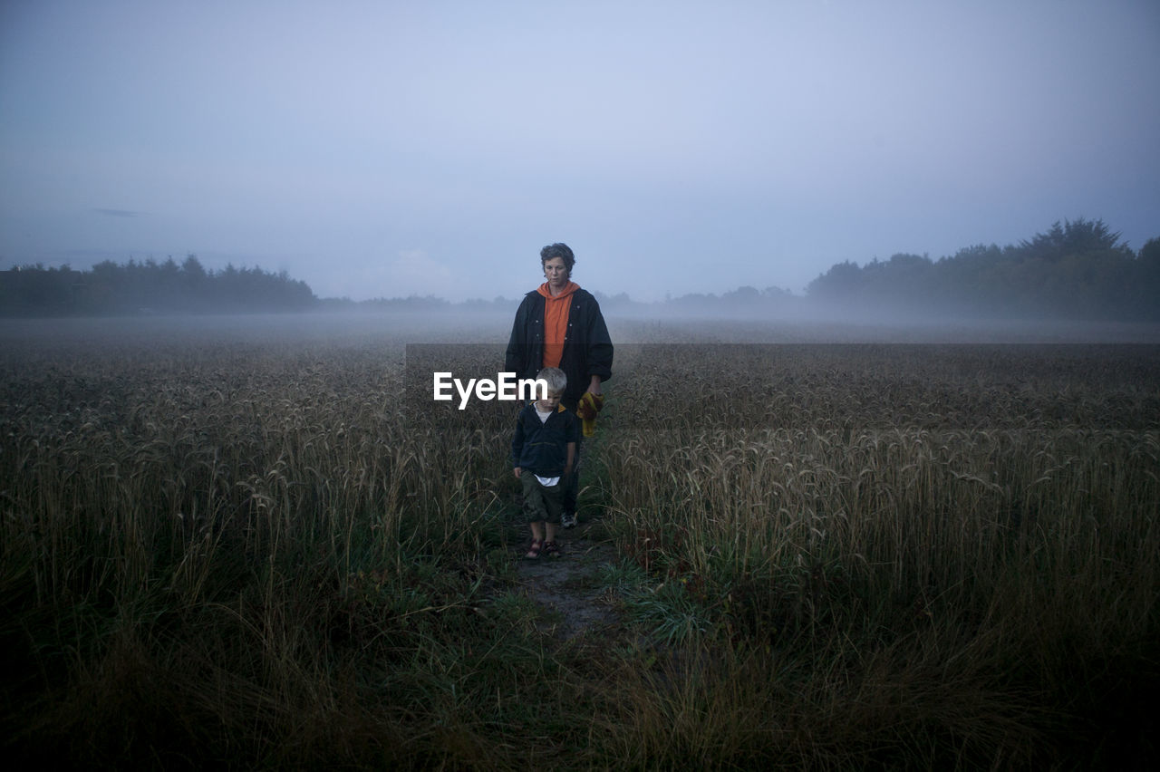 Mother walking with son through foggy meadow