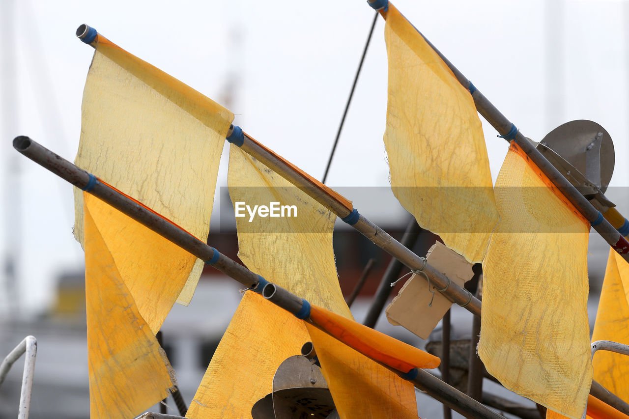 LOW ANGLE VIEW OF YELLOW FLAG ON WOODEN POST