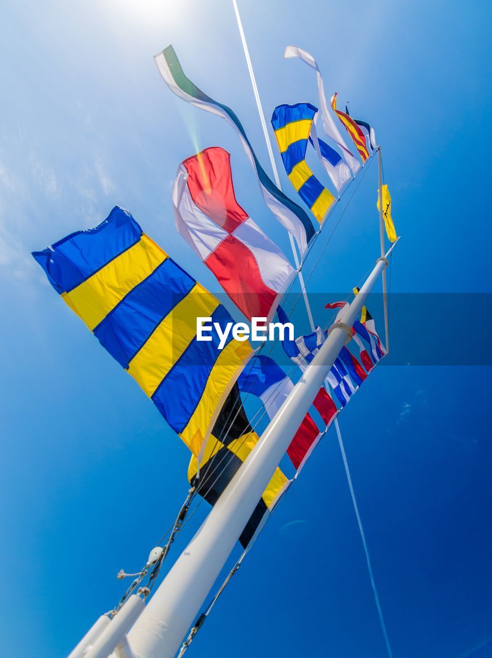 Low angle view of colorful flags against clear blue sky