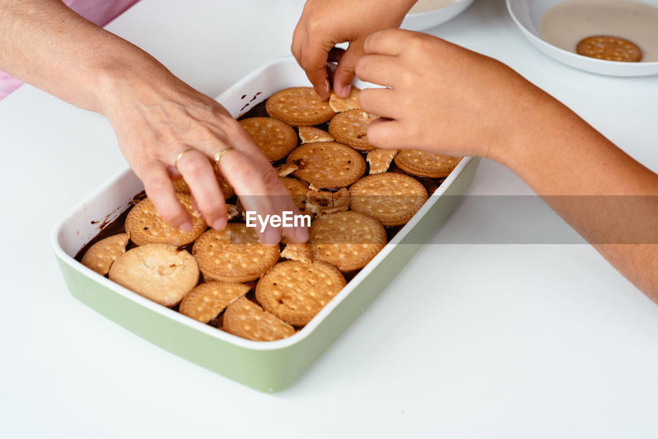 Cropped image of friends having cookies in container on table