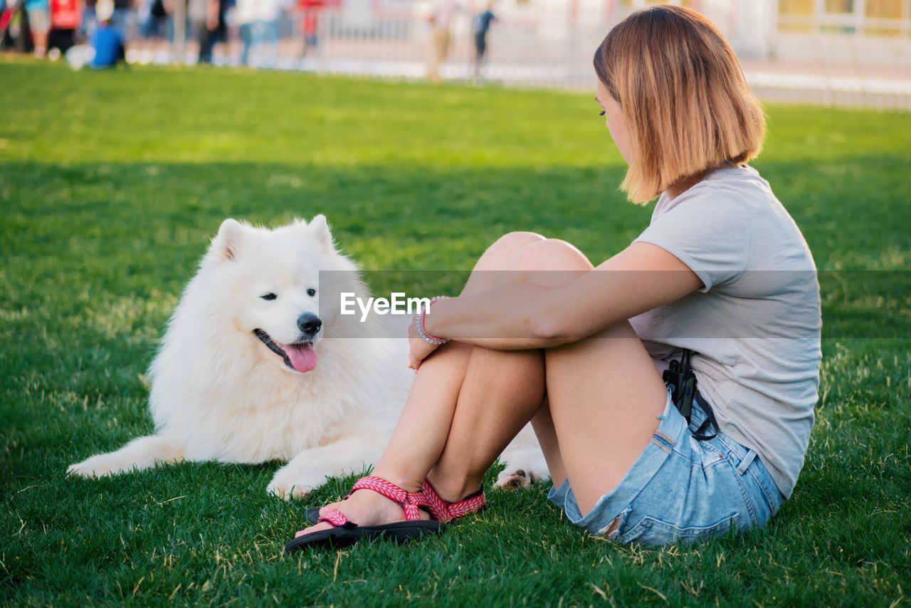 Young woman sitting with dog on field