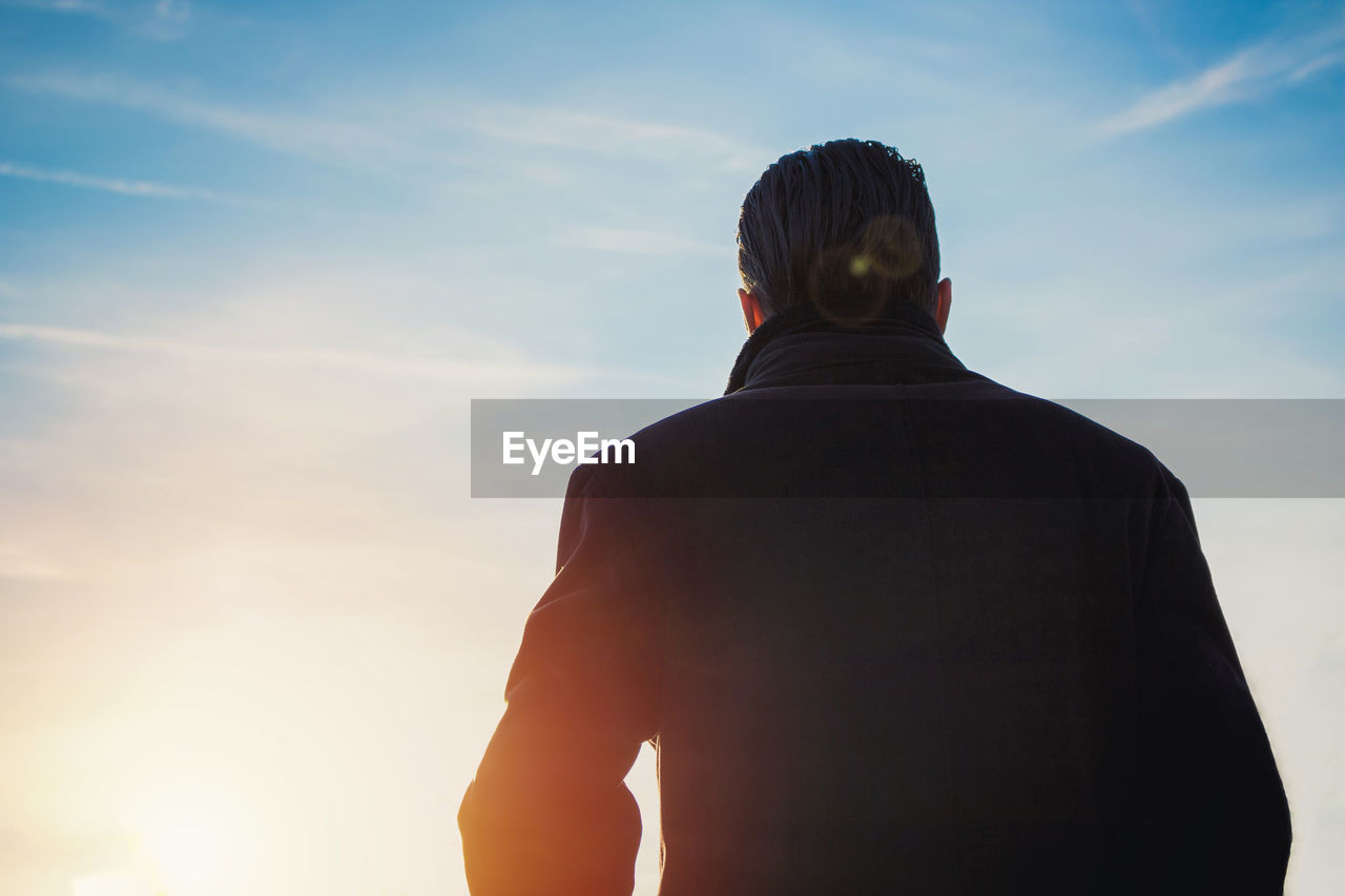 Rear view of man standing against sky during sunset