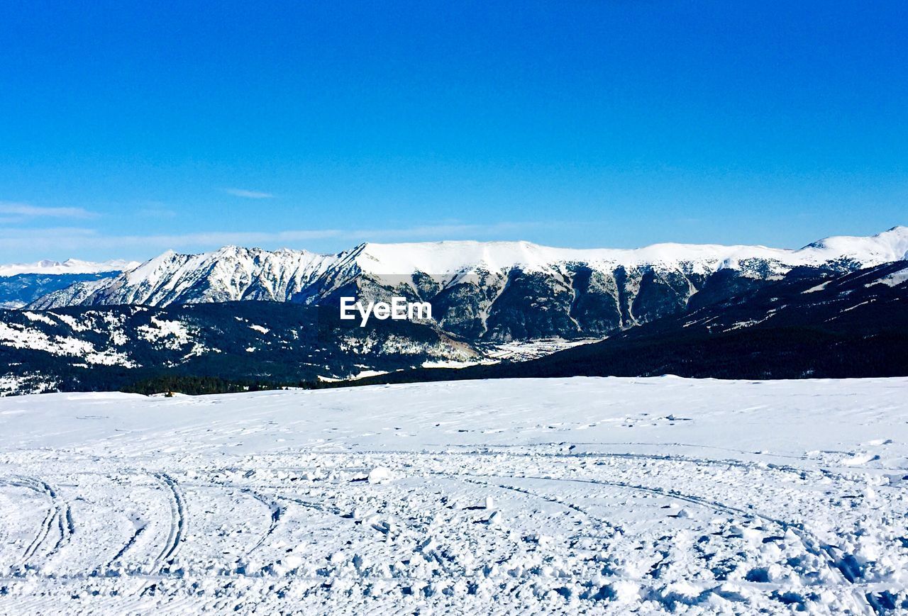 Scenic view of snowcapped mountains against blue sky