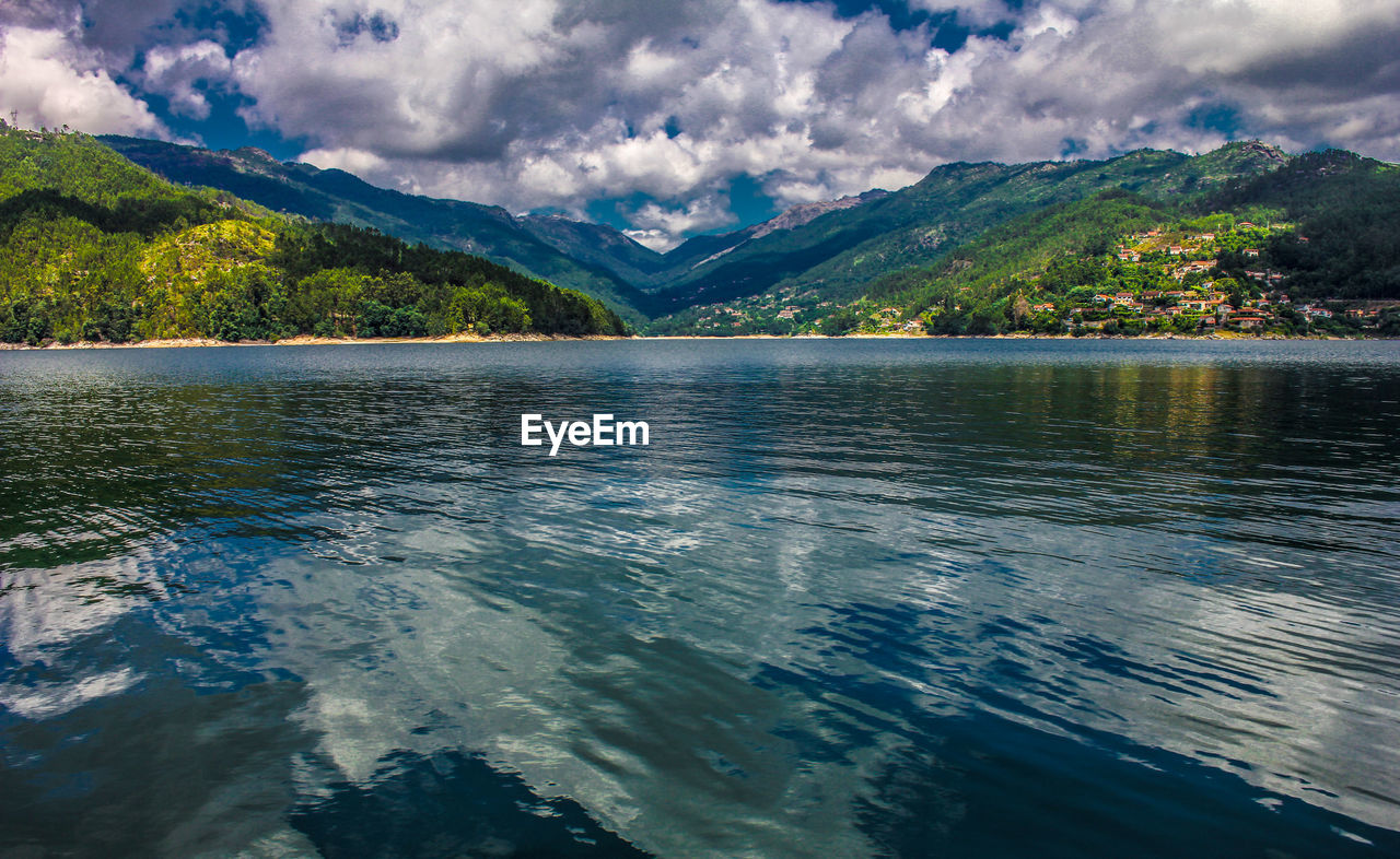 Scenic view of lake by mountains against sky