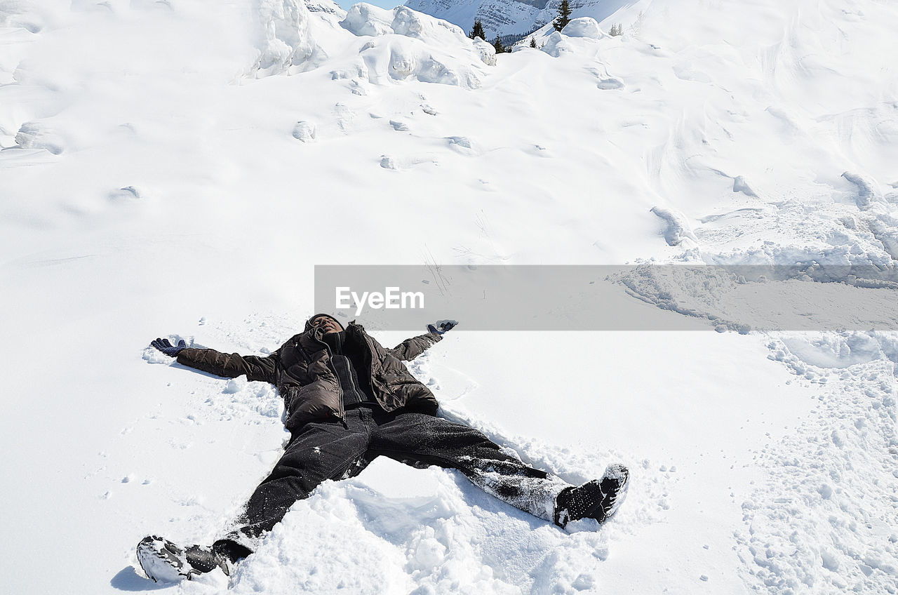 Man lying down on snow covered field