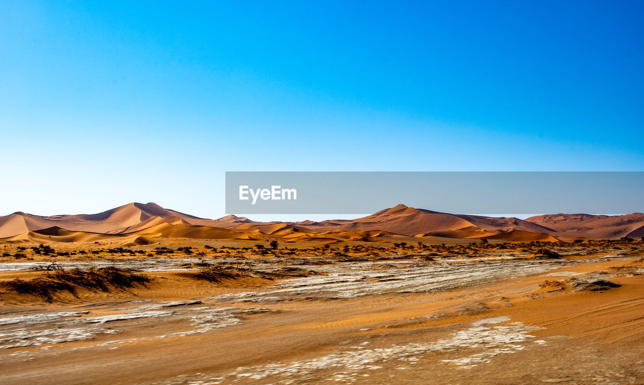 Scenic view of desert against clear blue sky