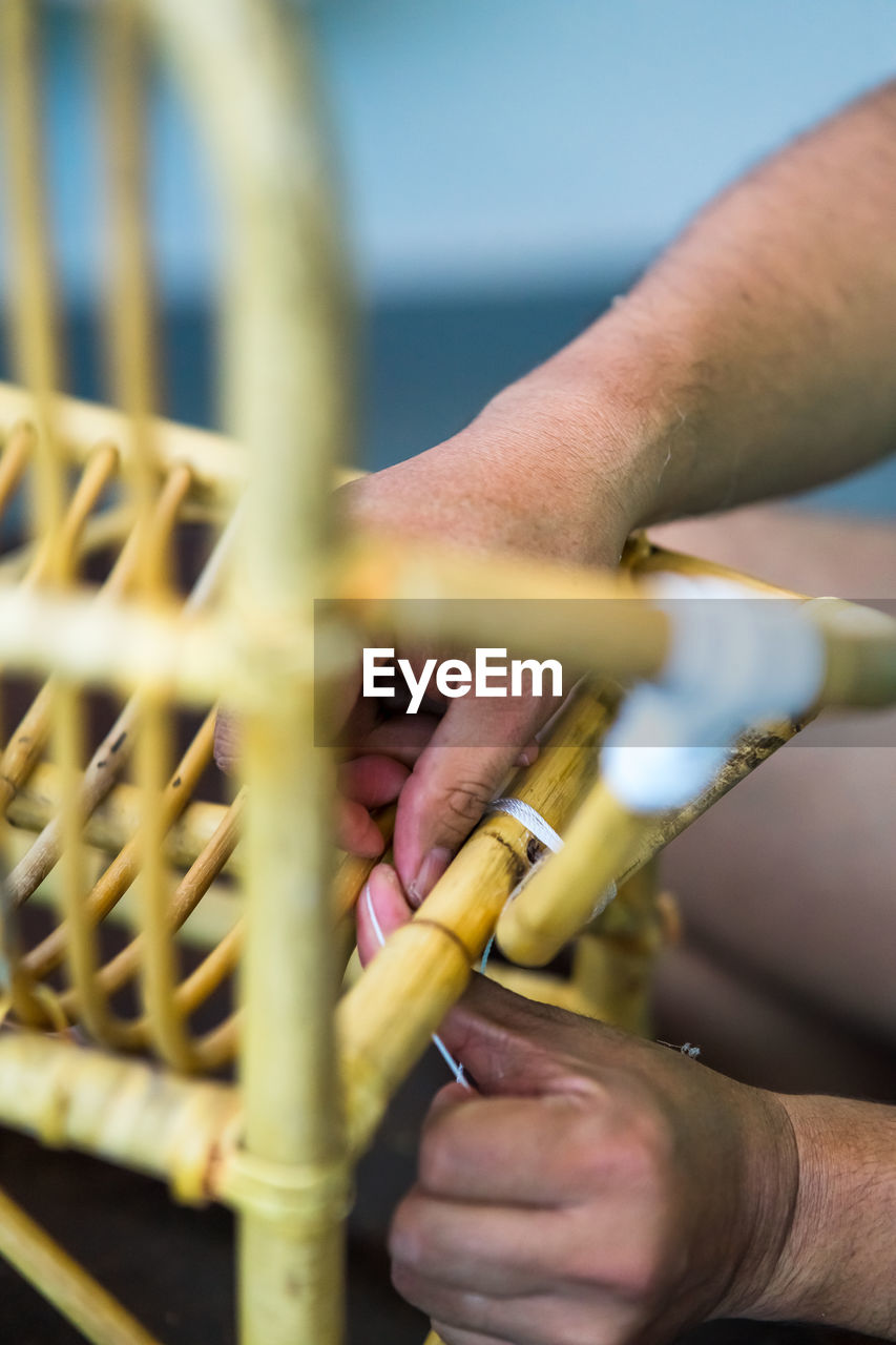 Cropped hands of man making wooden chair in workshop