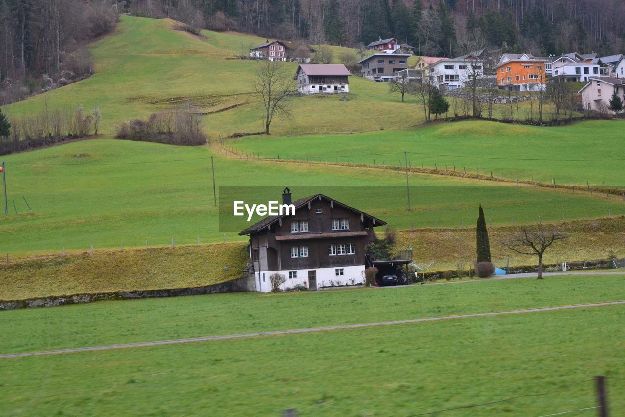 BARN ON GRASSY FIELD AGAINST HOUSES IN BACKGROUND