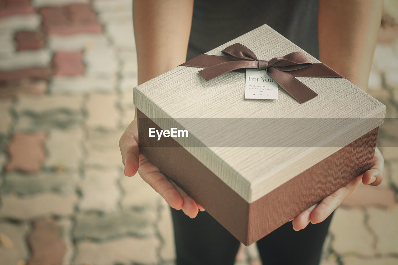 Midsection of woman holding gift box outdoors