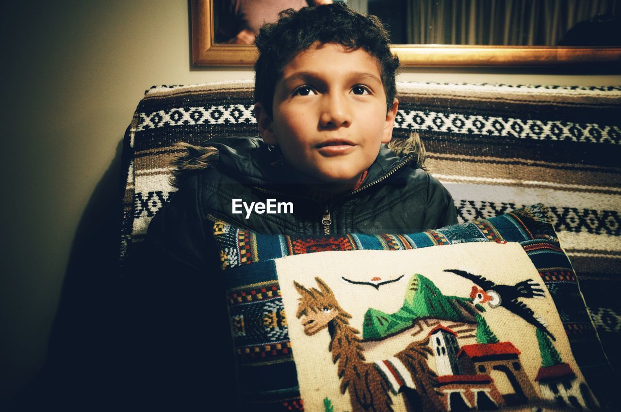 PORTRAIT OF BOY SITTING BY BOOK AT HOME