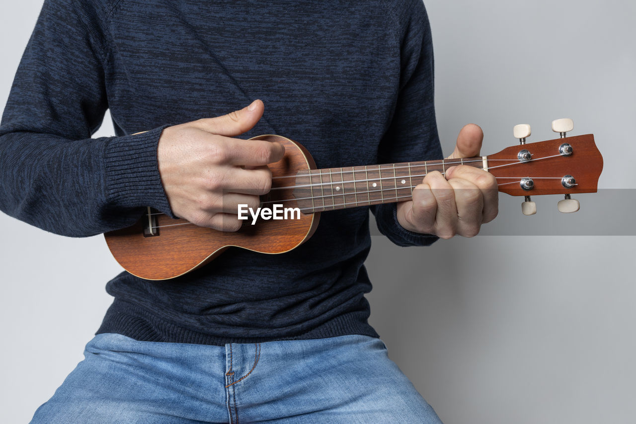 Midsection of man playing guitar