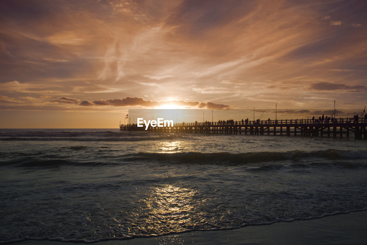 Scenic view of sea against cloudy sky during sunset