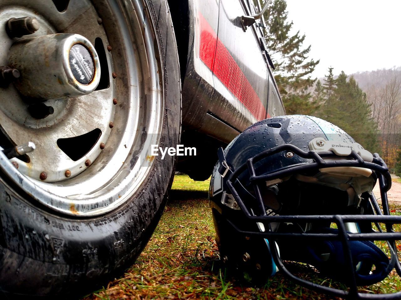 Close-up of helmet by truck on field during rainfall