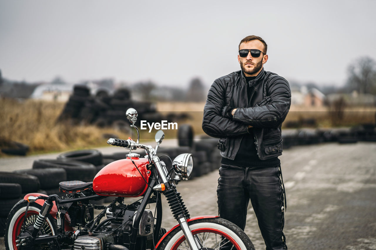 Full length of young man standing near bike