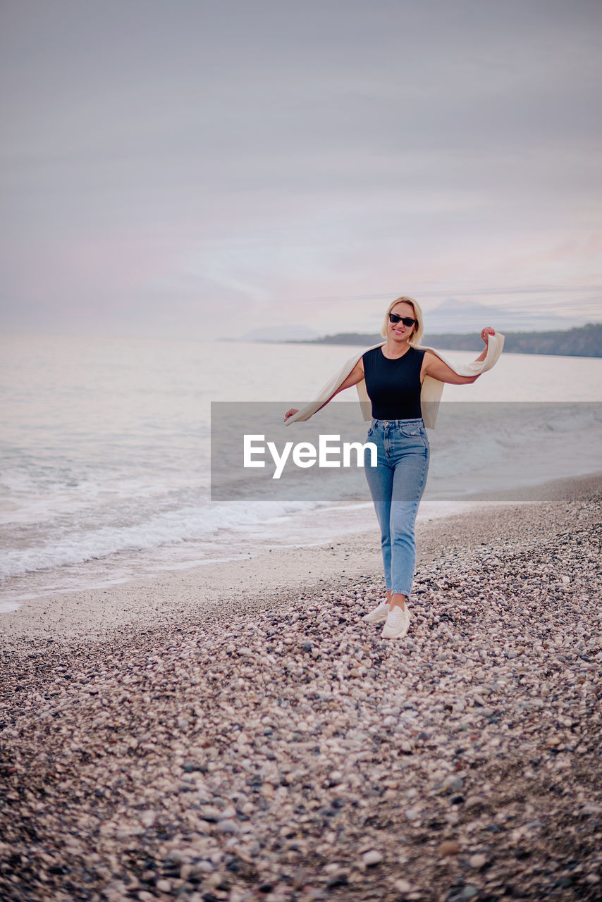 Full length of young woman standing at beach