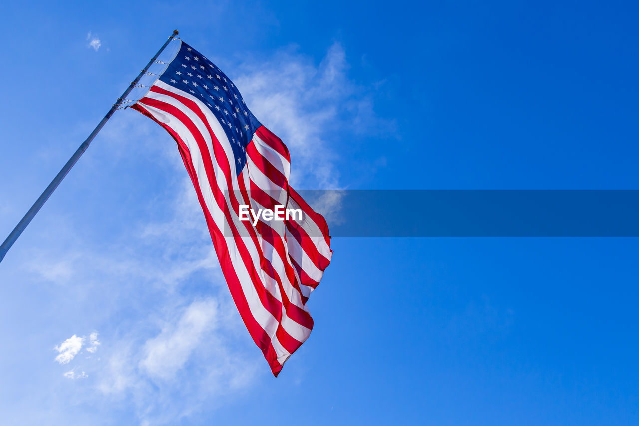 Low angle view of american flag against blue sky