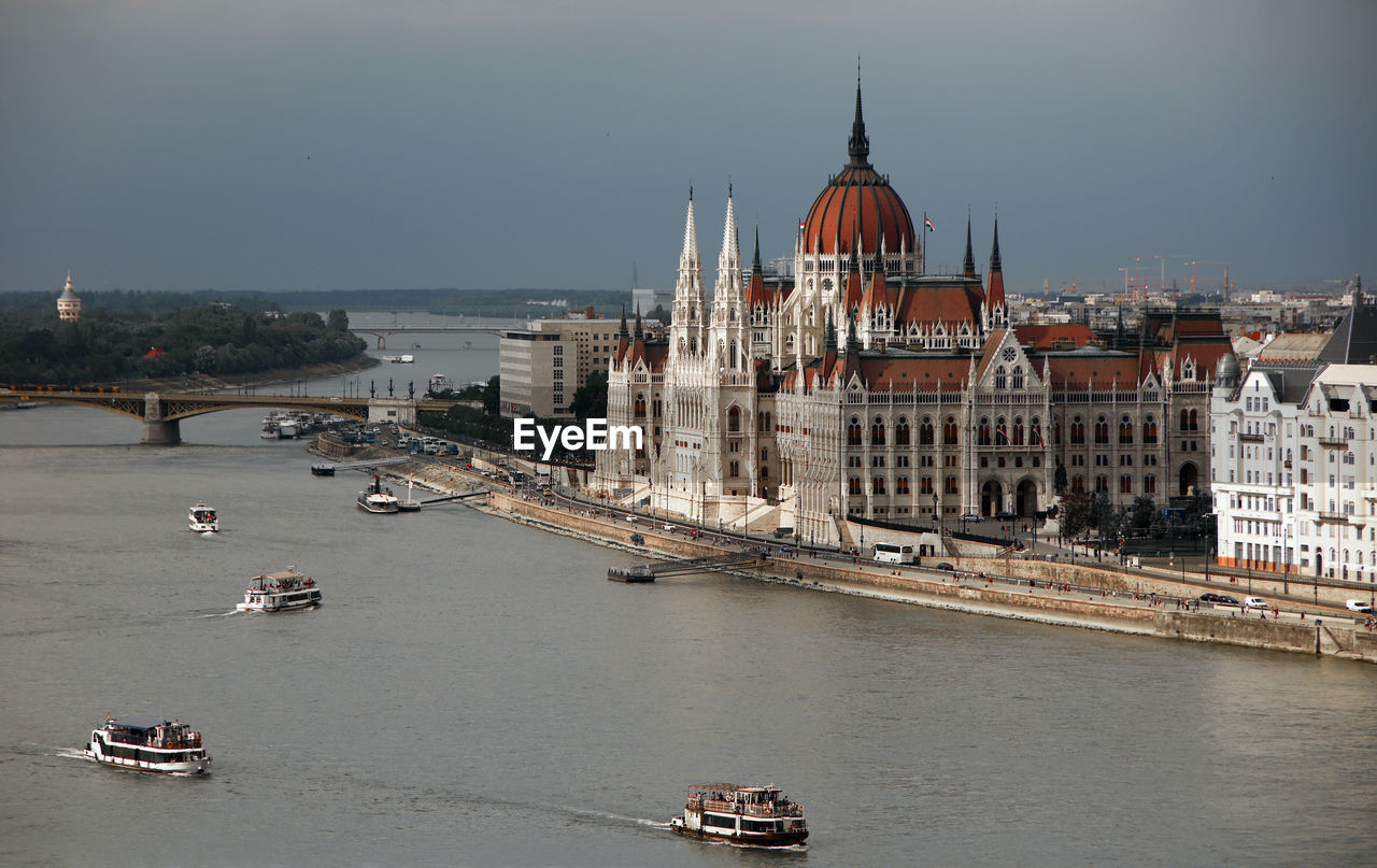 Boats in river by hungarian parliament building in city