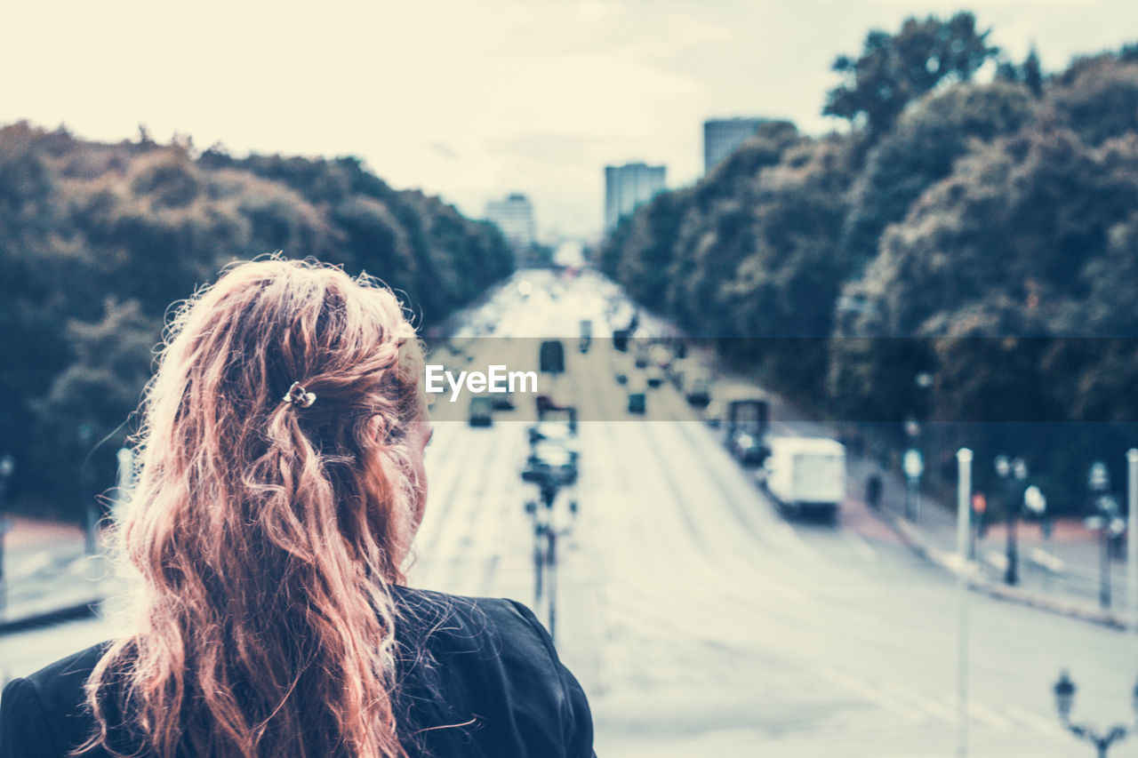 Rear view of woman overlooking a busy road