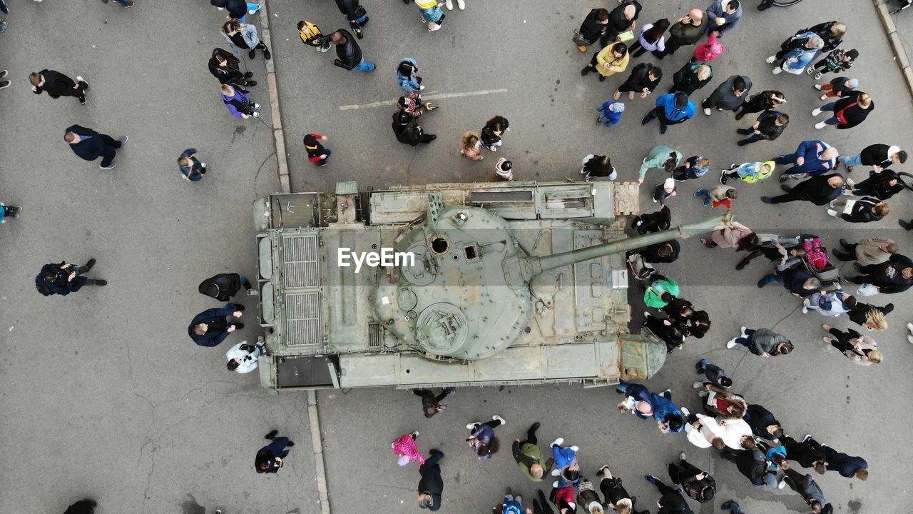 High angle view of people walking on street next to the wrecked russian fascist equipment