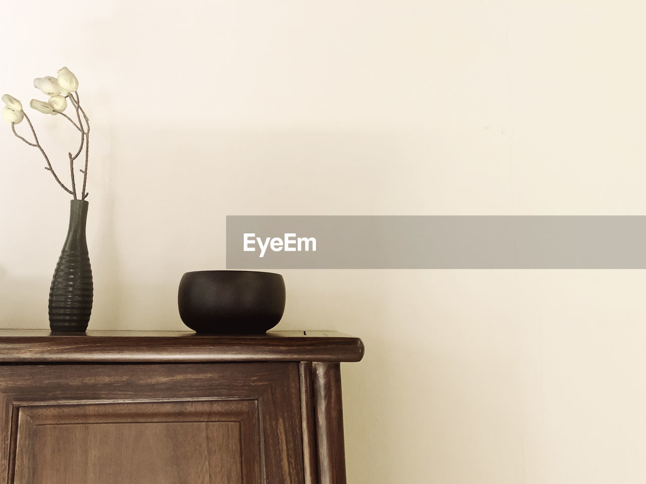 Close-up of vase on table against wall at home