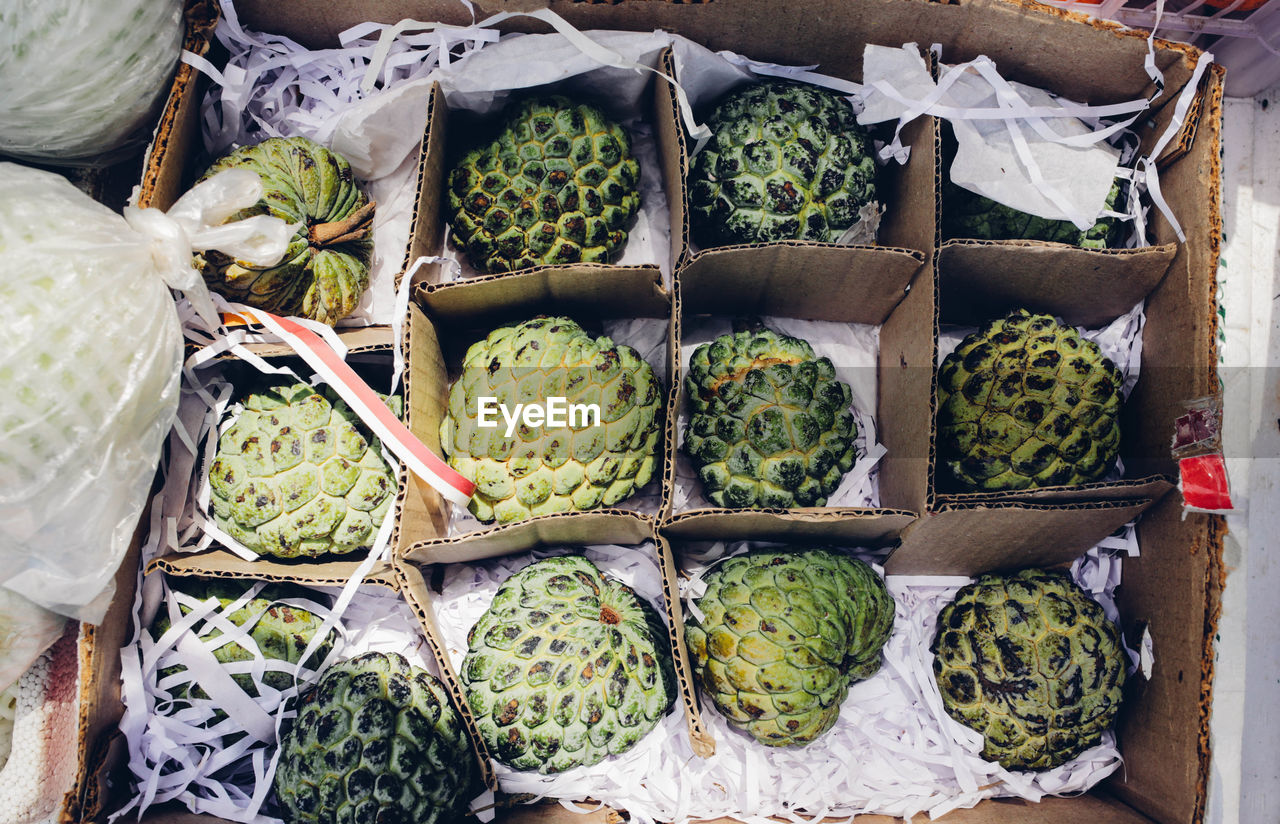 Directly above shot of custard apples in cardboard box at market