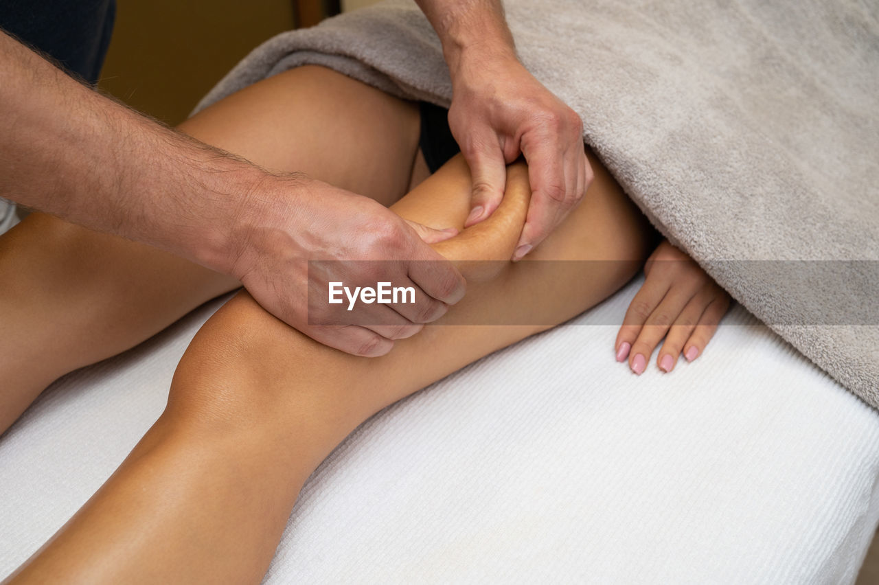 Cropped hands of massage therapist massaging woman in spa