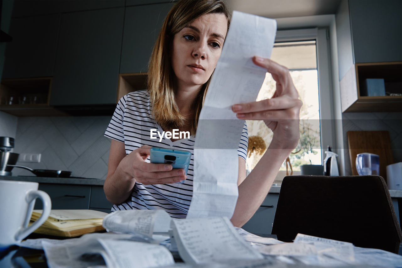 Woman looking at paper bill and counting expenses