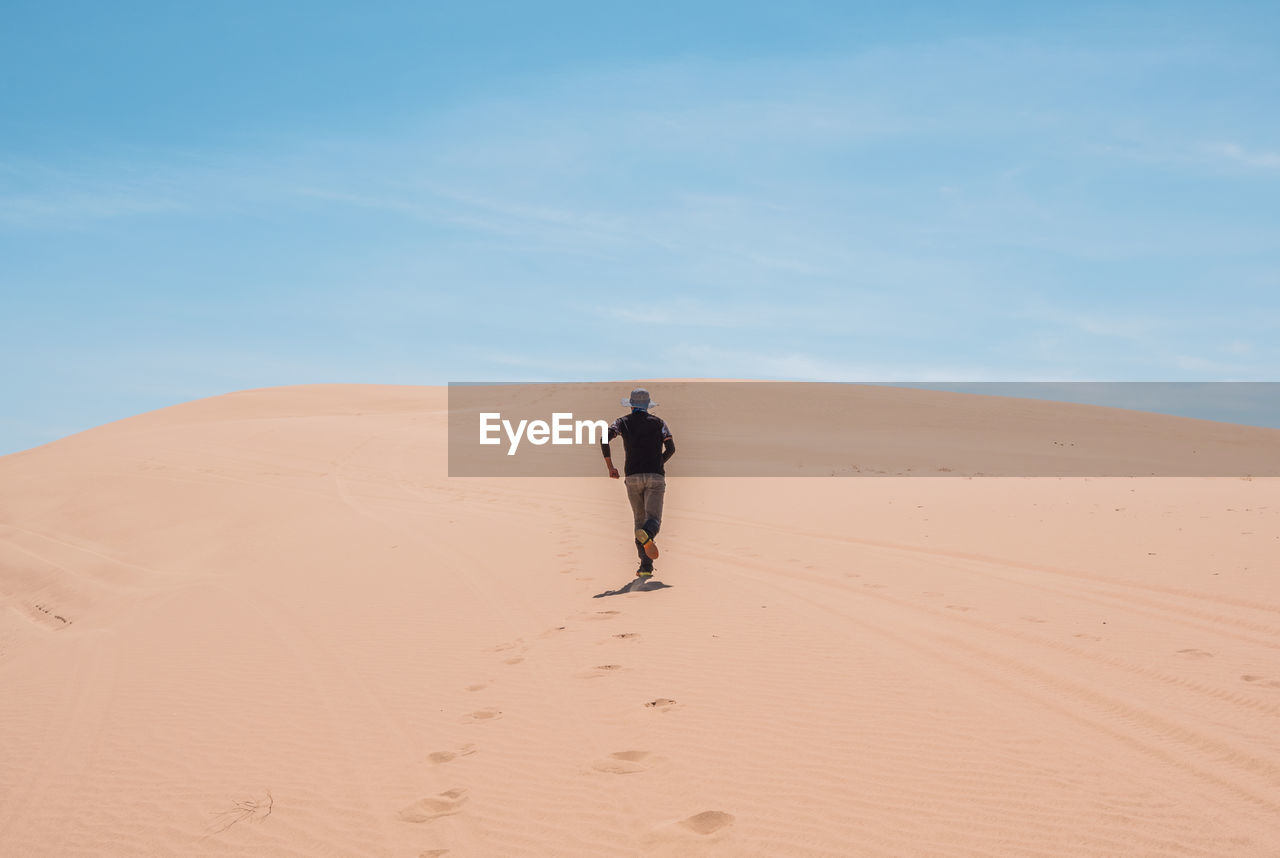 Man walking in desert against sky