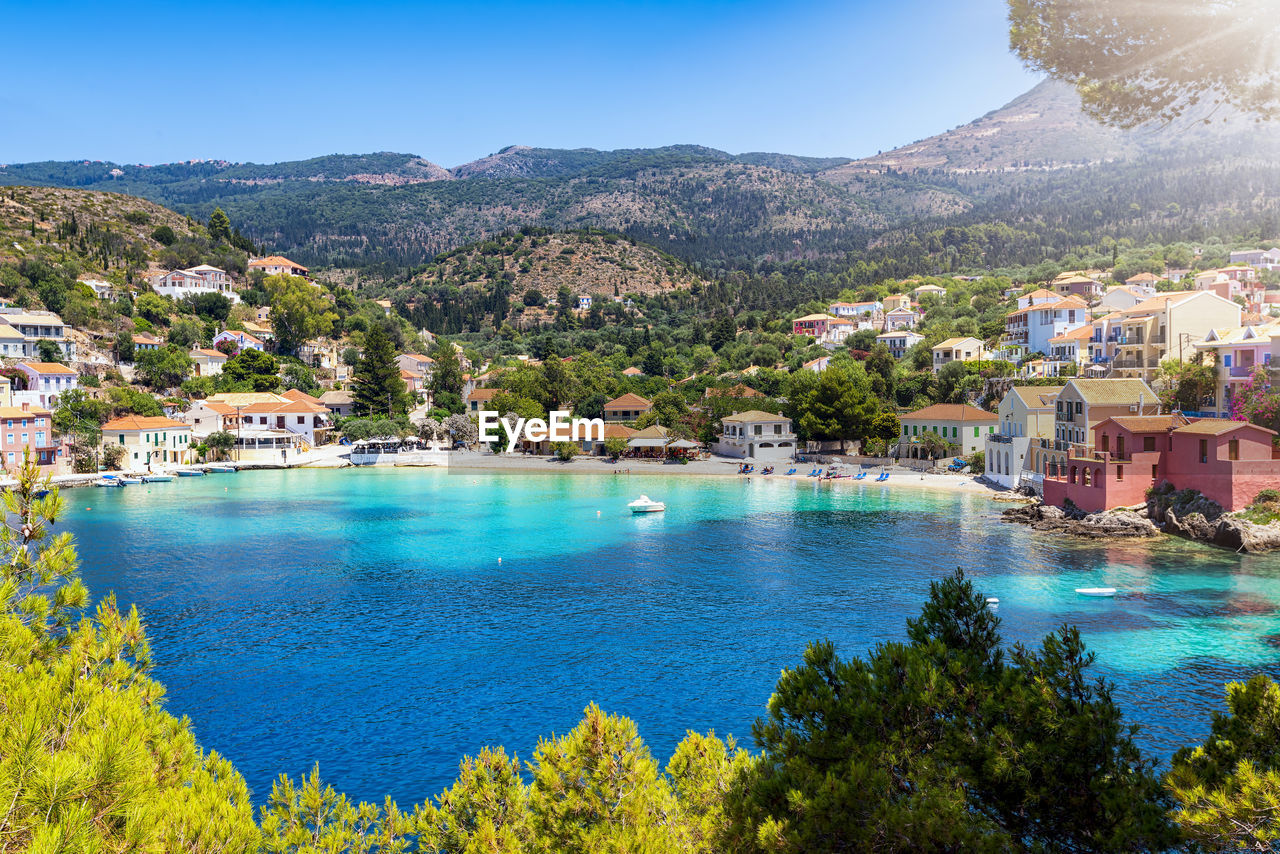 SCENIC VIEW OF SEA BY TOWNSCAPE AGAINST MOUNTAIN