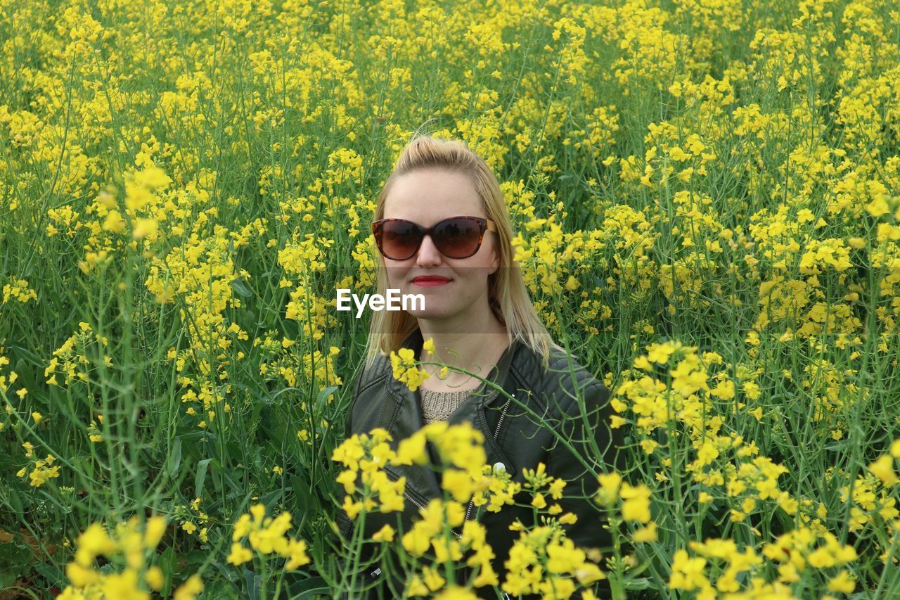 Woman standing in field of yellow flowers