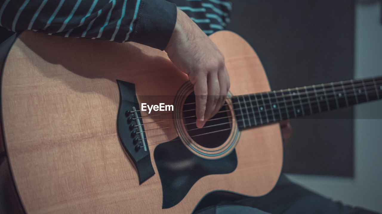 Midsection of man playing guitar