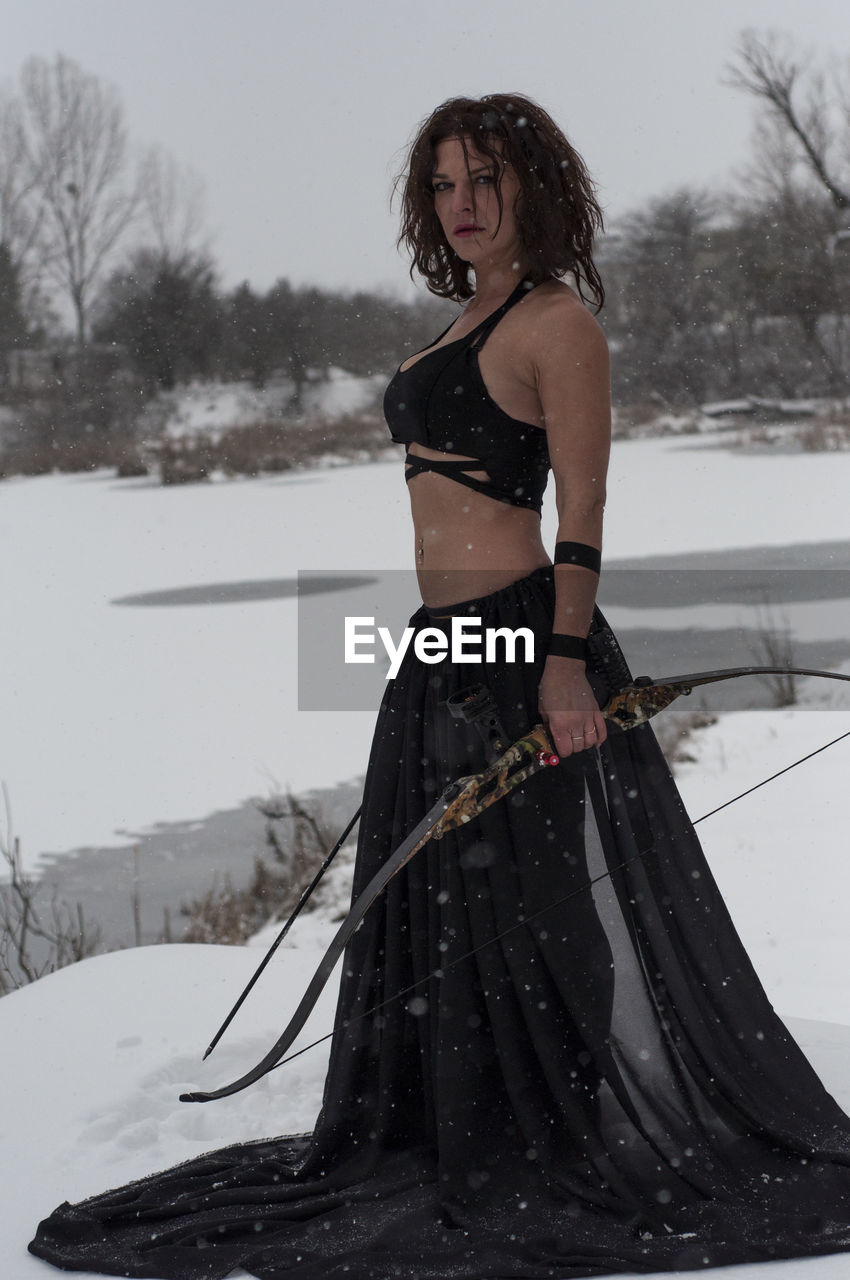 portrait of young woman standing on snow covered field during winter