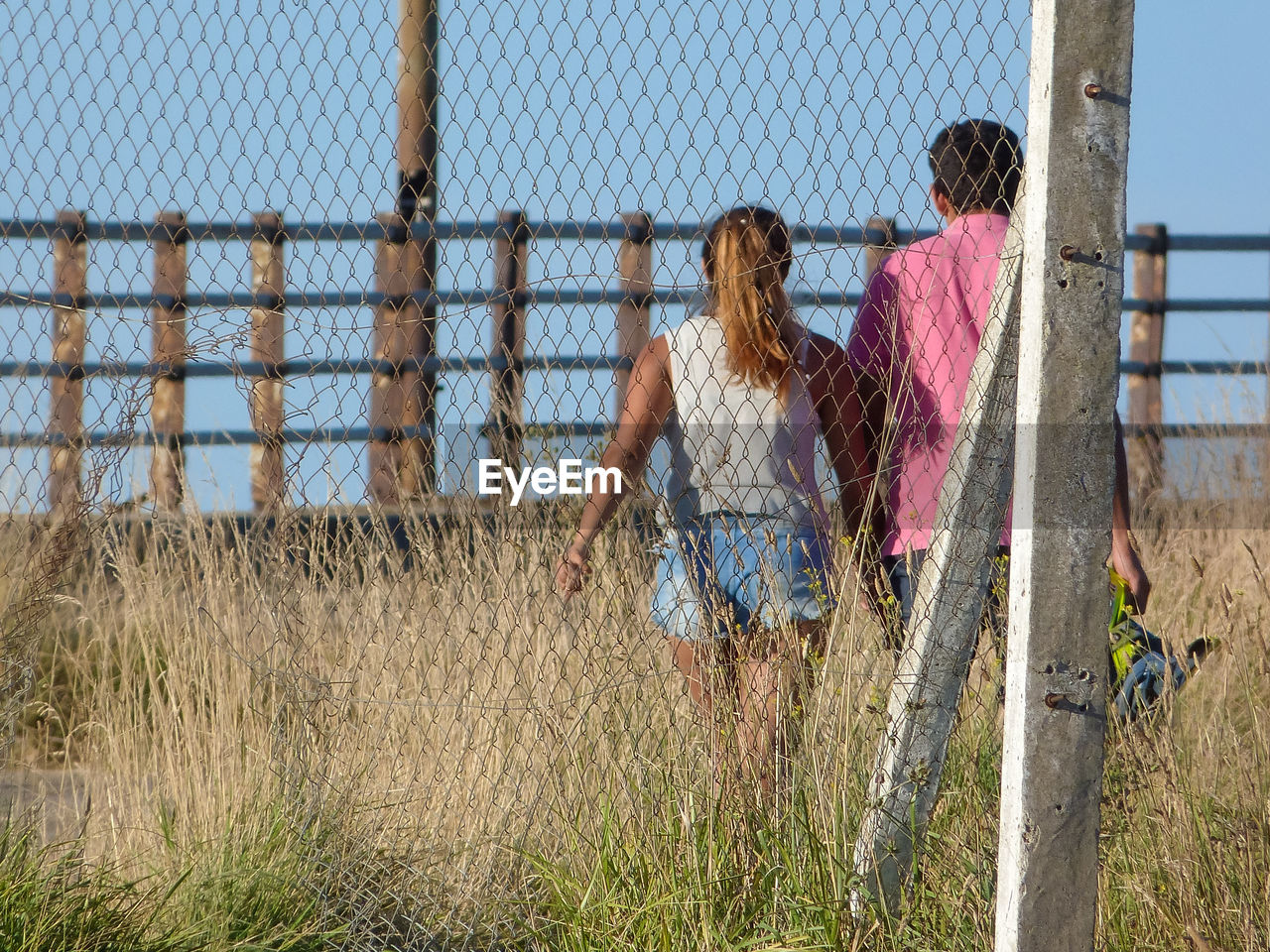 FULL LENGTH OF WOMAN STANDING BY FENCE