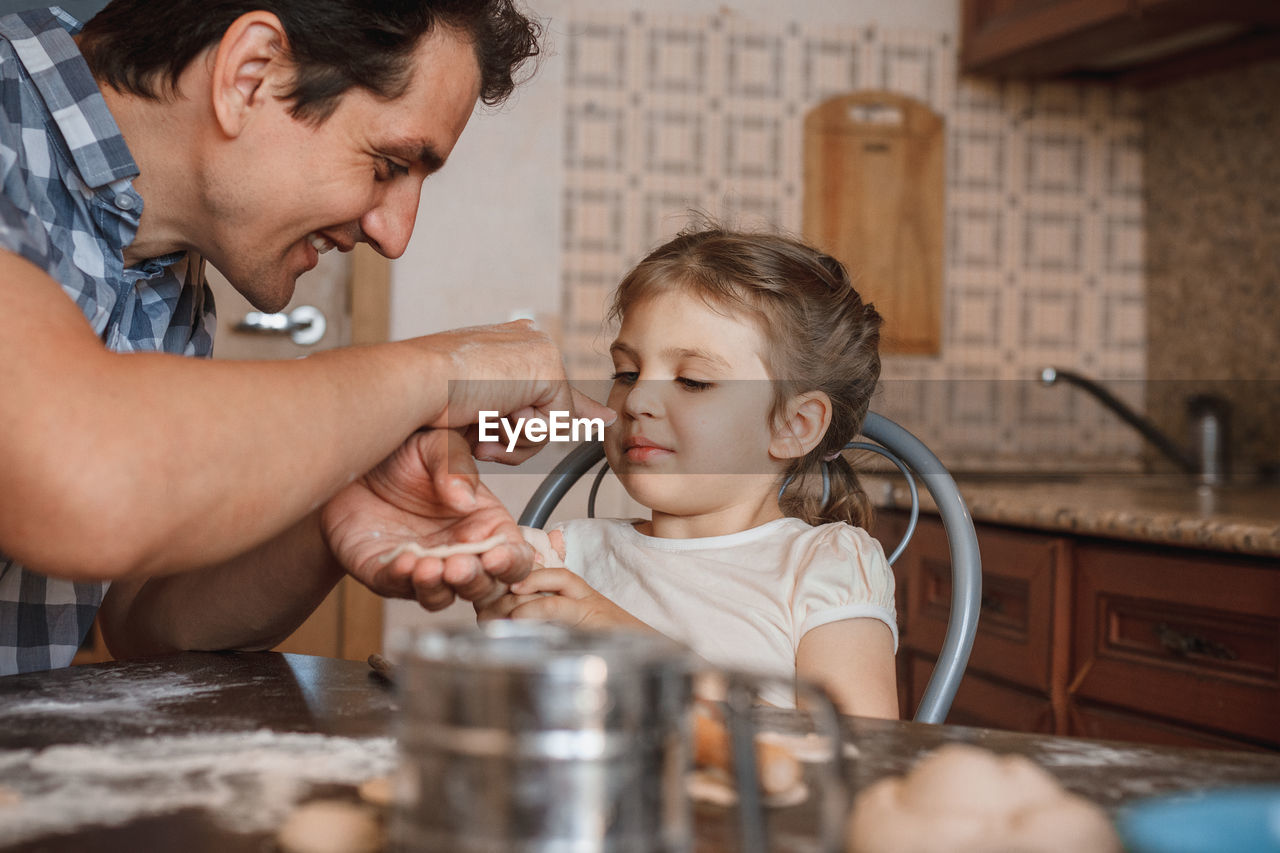 Cheerful father and daughter preparing food at home