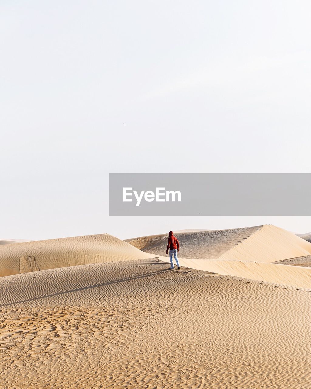 Full length of man walking on desert against clear sky