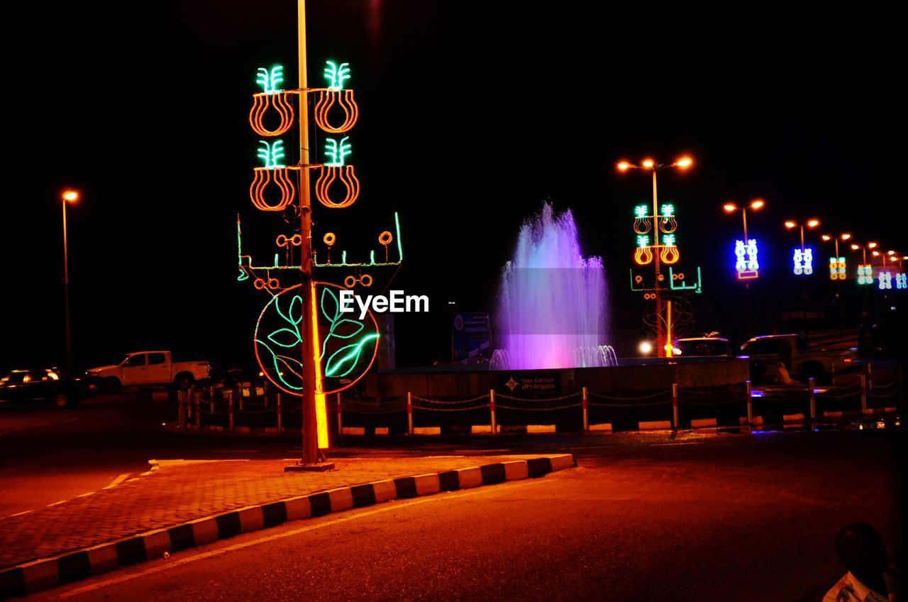 ILLUMINATED STREET LIGHTS AGAINST BUILDINGS AT NIGHT