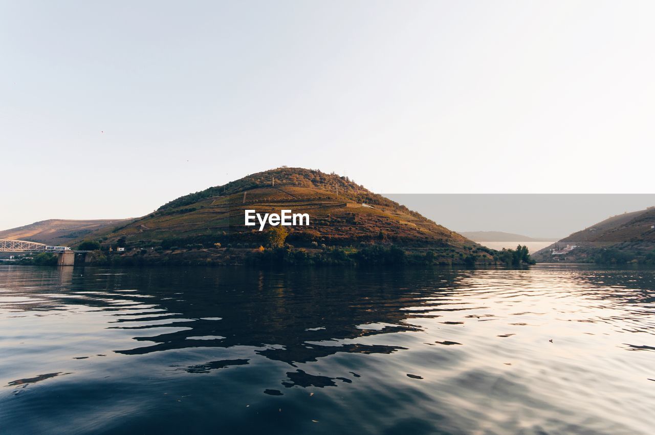 SCENIC VIEW OF LAKE BY MOUNTAIN AGAINST CLEAR SKY