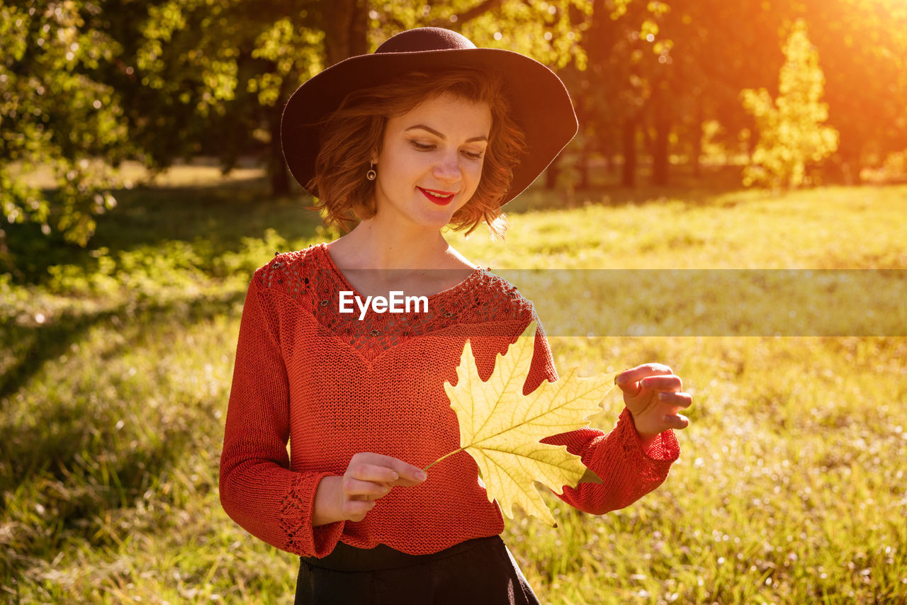 WOMAN WEARING HAT STANDING BY PLANTS