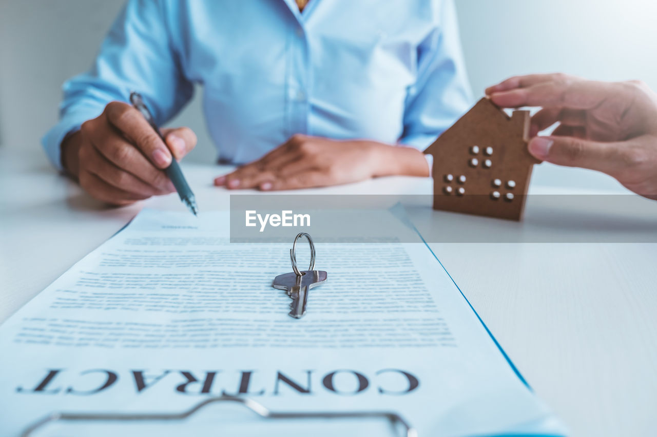 midsection of doctor writing on paper at table