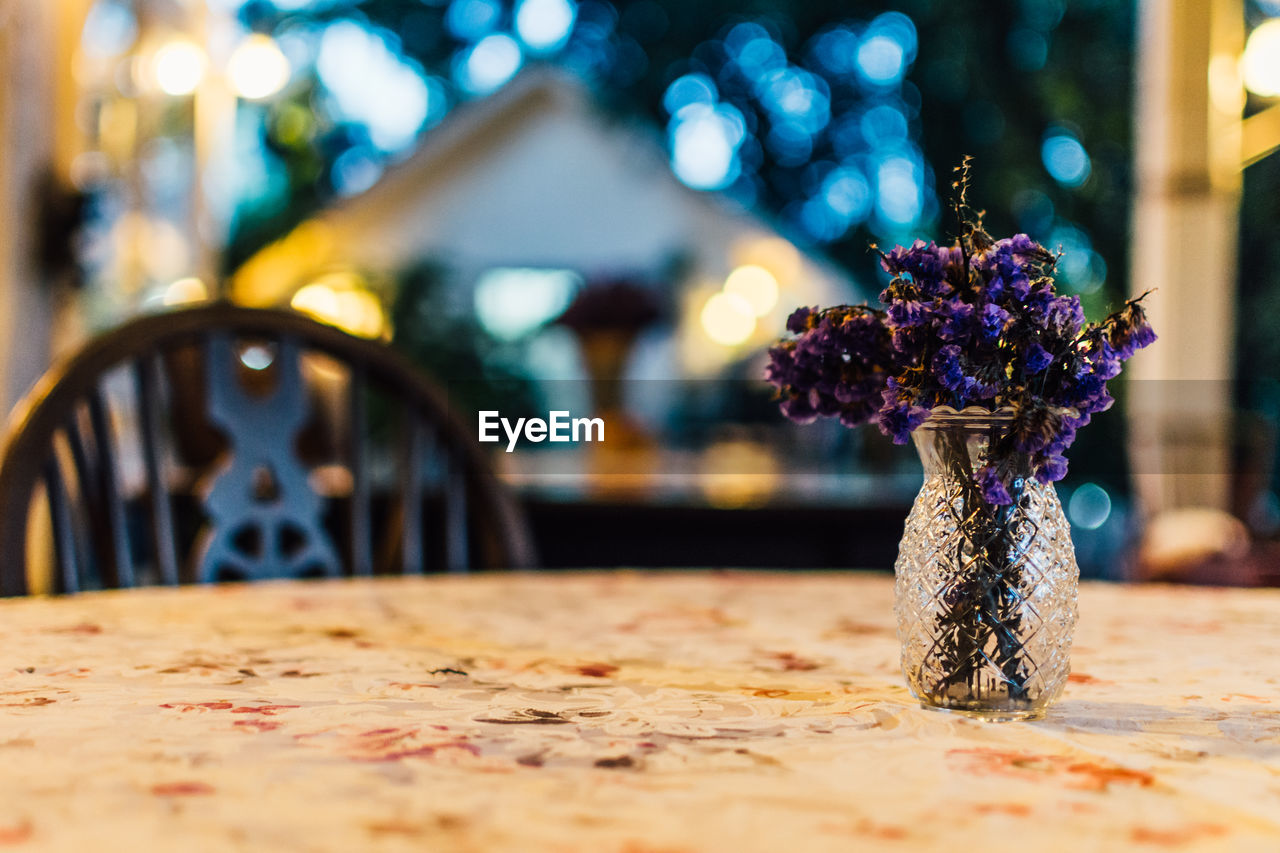 Purple flowers in vase on table at porch during dusk